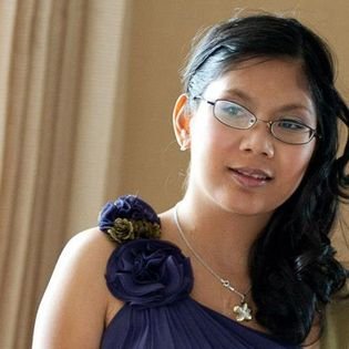 Photo in Hawai'i. Charlene has light brown skin, with glasses. She is wearing a blue and white dress.