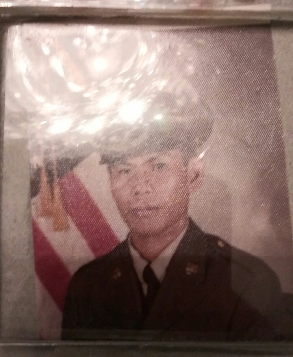 A photo of with a American flag and a light brown male in a military suit.